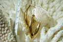Elongated gold-tone crescent hoop earrings with tapered ends and smooth reflective surfaces.