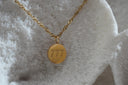 Alternate view: gold-tone chain with a round pendant engraved 777.