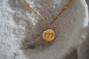 Gold-tone chain with a round pendant engraved 777.