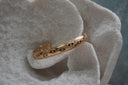 Gold-tone open cuff with black eye motifs, white centres and raised radiating details.