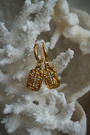 Gold-tone hoops with textured rectangular charms and crosses formed from clear accents.