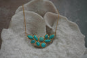 Gold-tone chain necklace with a cluster of blue veined oval, teardrop and rounded-square centres in gold-tone borders.
