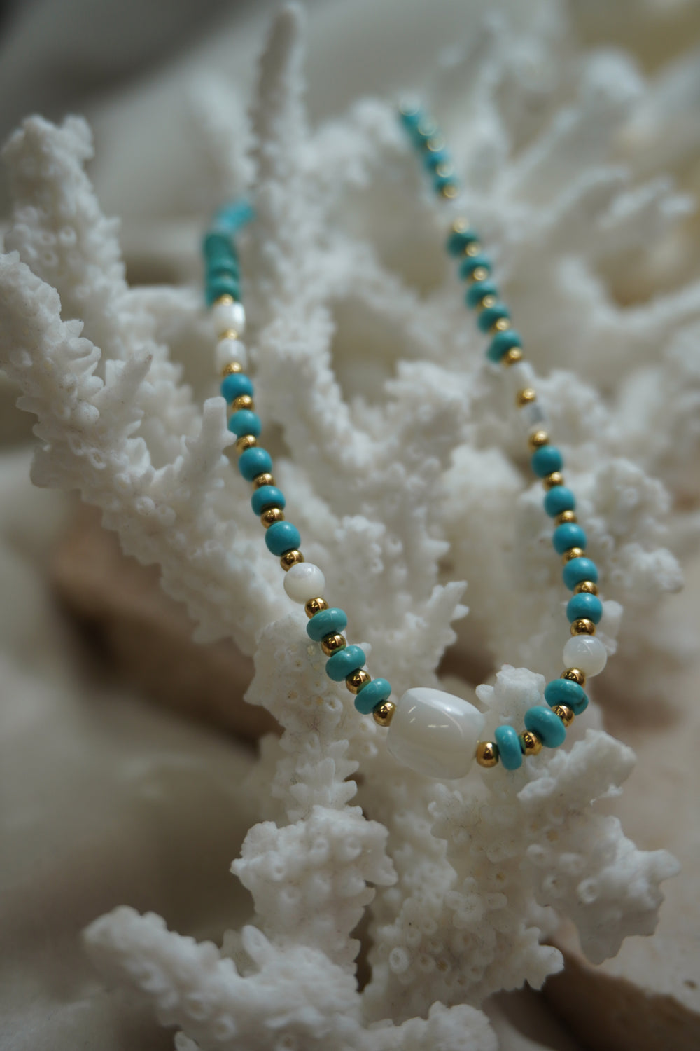 Necklace with blue disc-shaped beads, gold-tone spacers, white round beads and a rounded-square white centre bead.