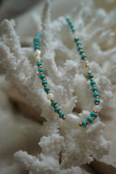Necklace with blue disc-shaped beads, gold-tone spacers, white round beads and a rounded-square white centre bead.