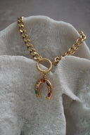Alternate view: gold-tone chain bracelet with a horseshoe charm set with multicoloured accents beneath a round connector.