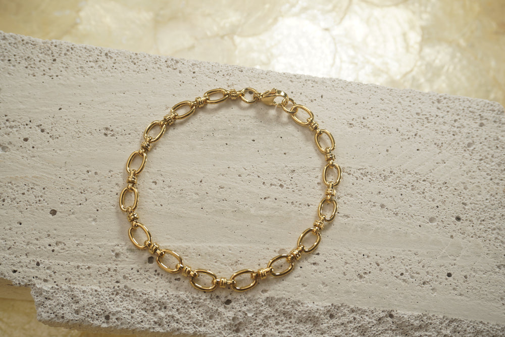 Gold-tone bracelet with fine oval links, small ridged connectors and a clasp.
