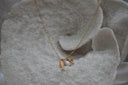 Gold-tone necklace with a textured fish charm, clear-accent palm tree and white oval bead.