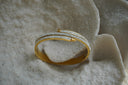 Alternate view: gold-tone hinged bangle with overlapping nail-like bars and rows of small clear accents.