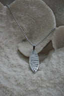 Silver-tone chain necklace with a surfboard-shaped pendant bearing SURFING lettering.