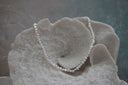 Necklace of closely strung irregular white beads with an iridescent appearance.
