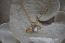 Alternate view: gold-tone necklace with a ridged shell charm, radiating open heart and white heart bead with blue flowers.