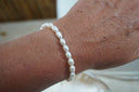 Alternate view: white oval-bead bracelet shown on a wrist.