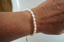 White oval-bead bracelet shown on a wrist.