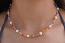 On-body view: necklace with multicoloured small beads, gold-tone spacers and rounded white beads.