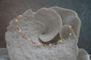 Necklace with multicoloured small beads, gold-tone spacers and rounded white beads.