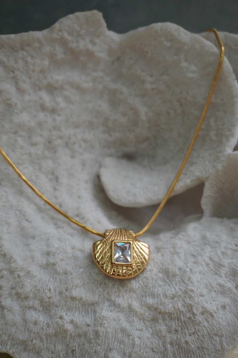 Gold-tone necklace with a shell-shaped pendant and clear-looking rectangular centre.