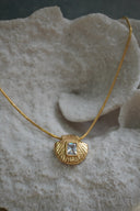 Gold-tone necklace with a shell-shaped pendant and clear-looking rectangular centre.