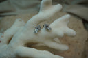 Silver-tone cross-shaped stud earrings with round clear accents and larger teardrop accents below.