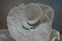 Gold-tone necklace with elongated links, irregular turquoise-coloured beads and a small heart charm.