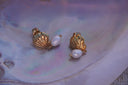 Gold-tone fluted shell-inspired stud earrings with hanging white oval beads.