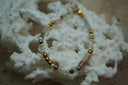 Bracelet with pale aqua, green and white beads, gold-tone spheres and a long mottled accent.