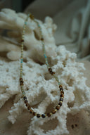 Necklace with brown and pale green faceted beads, small blue accents and gold-tone spacers.