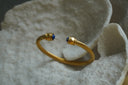 Alternate view: gold-tone open cuff with rope-like ridges and rounded blue accents at both ends.