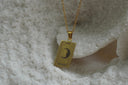Gold-tone necklace with a rectangular The Moon pendant, crescent face, radiating marks and XVIII lettering.