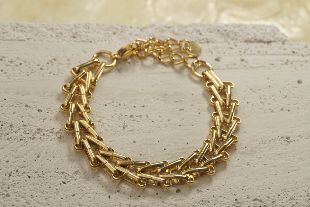 Gold-tone bracelet with overlapping angular bar links, a clasp and extension chain.