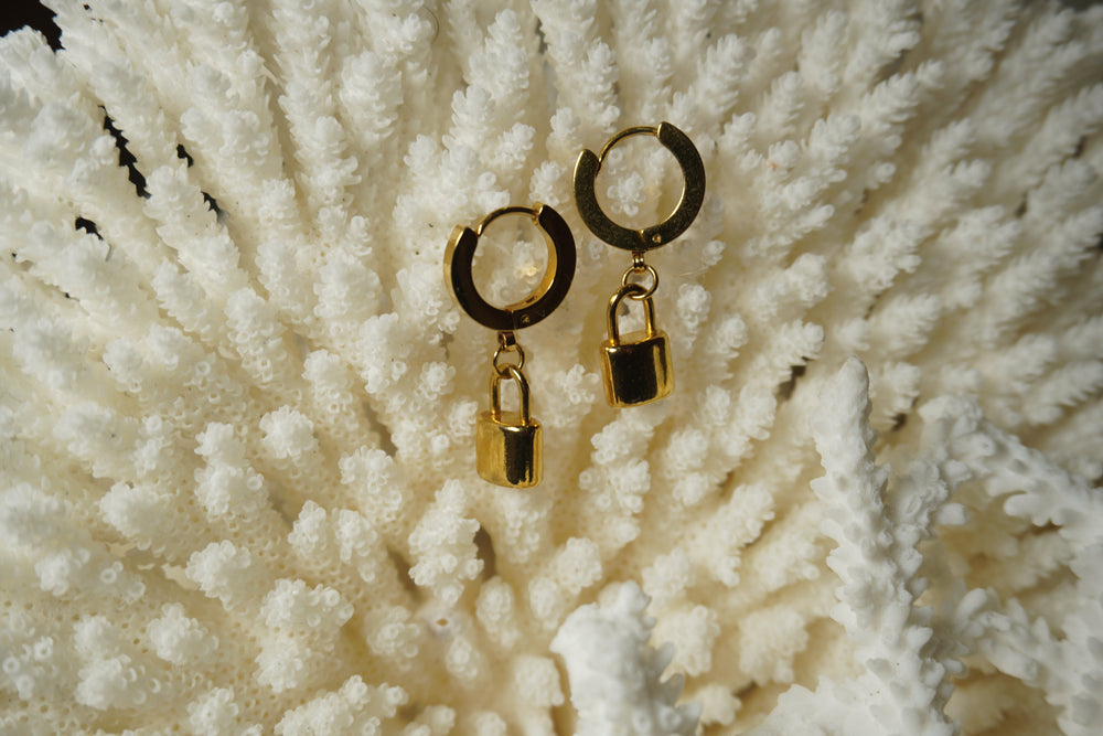 Gold-tone hoop earrings with smooth rectangular padlock charms and curved lock tops.