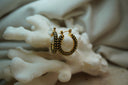 Gold-tone hoop earrings covered in rows of dark green round accents.