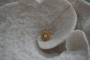 Gold-tone sunflower pendant necklace with pointed petals and a clear round faceted centre.