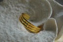 Gold-tone open cuff with three broad rounded lengthwise ridges.