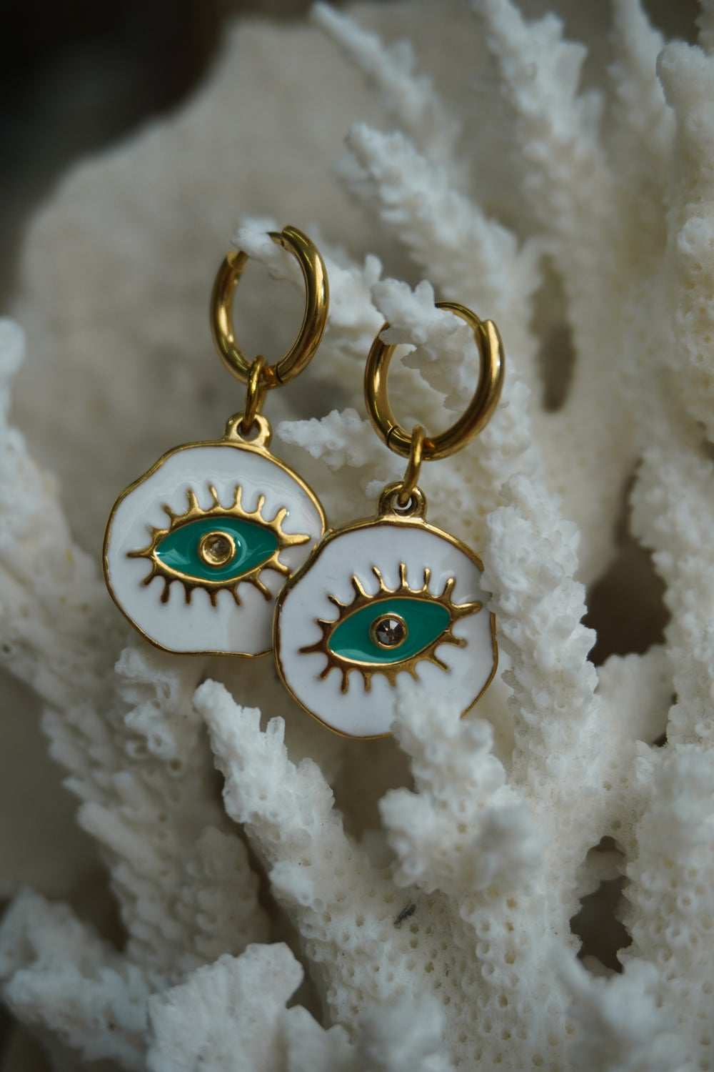 Alternate view: gold-tone hoops with irregular white disc charms, green eye motifs and raised lashes.