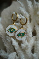Alternate view: gold-tone hoops with irregular white disc charms, green eye motifs and raised lashes.