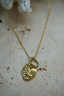 Alternate view: gold-tone necklace with an irregular medallion showing a seated figure and crescent, beside a clear-accent star charm.