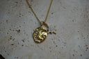 Gold-tone necklace with an irregular medallion showing a seated figure and crescent, beside a clear-accent star charm.