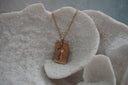 Gold-tone chain necklace with a rectangular tag and a key charm with a star-shaped head.