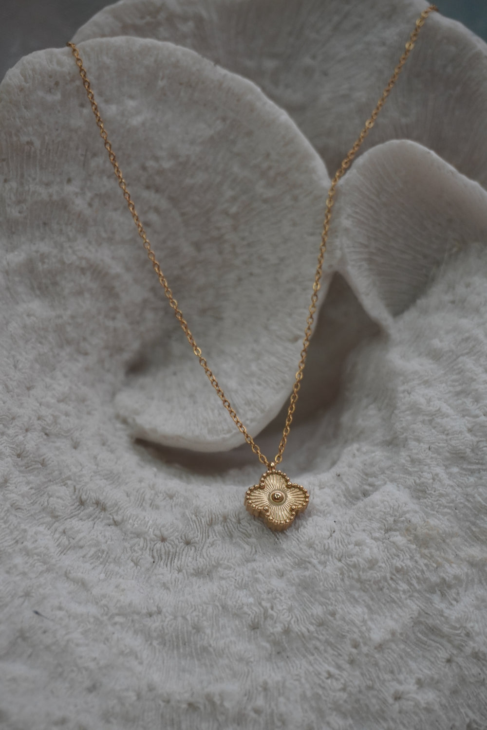 Alternate view: gold-tone necklace with a four-lobed pendant, radiating texture, dotted border and raised round centre.