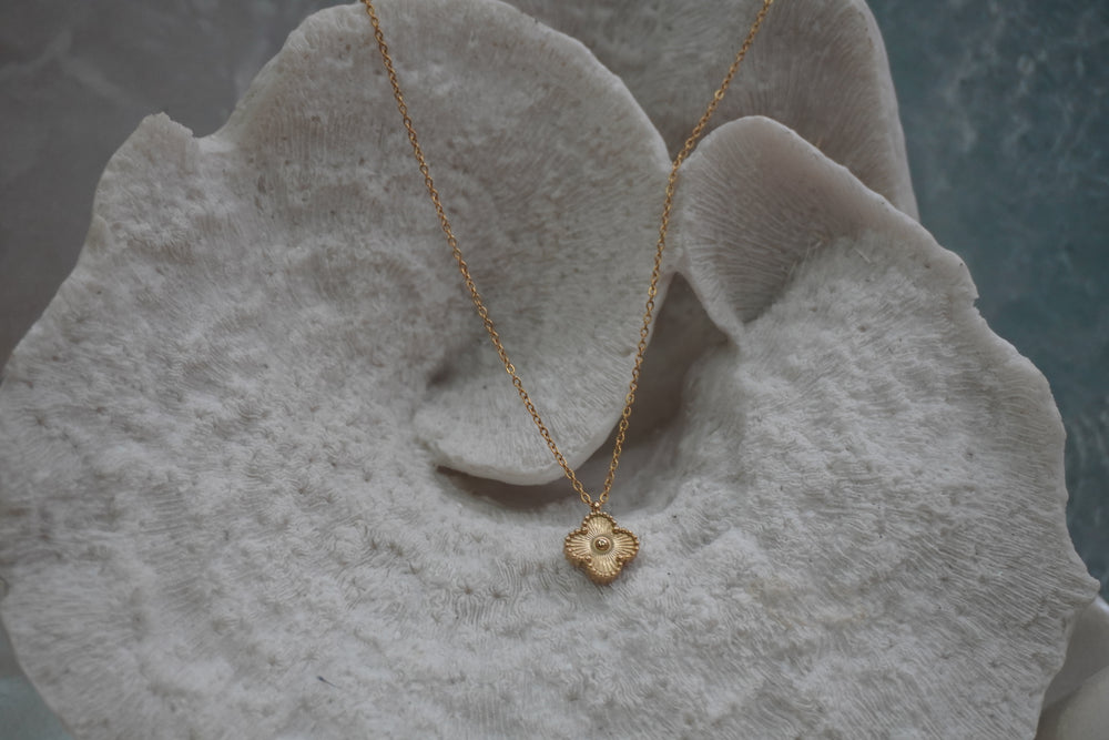 Gold-tone necklace with a four-lobed pendant, radiating texture, dotted border and raised round centre.