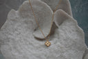 Gold-tone necklace with a four-lobed pendant, radiating texture, dotted border and raised round centre.