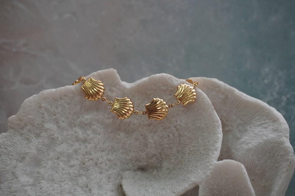 Gold-tone bracelet with a row of ridged fan-shell motifs.