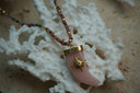 Alternate view: beaded necklace with a pale pink curved horn-shaped pendant, gold-tone cap and star detail with a clear centre.