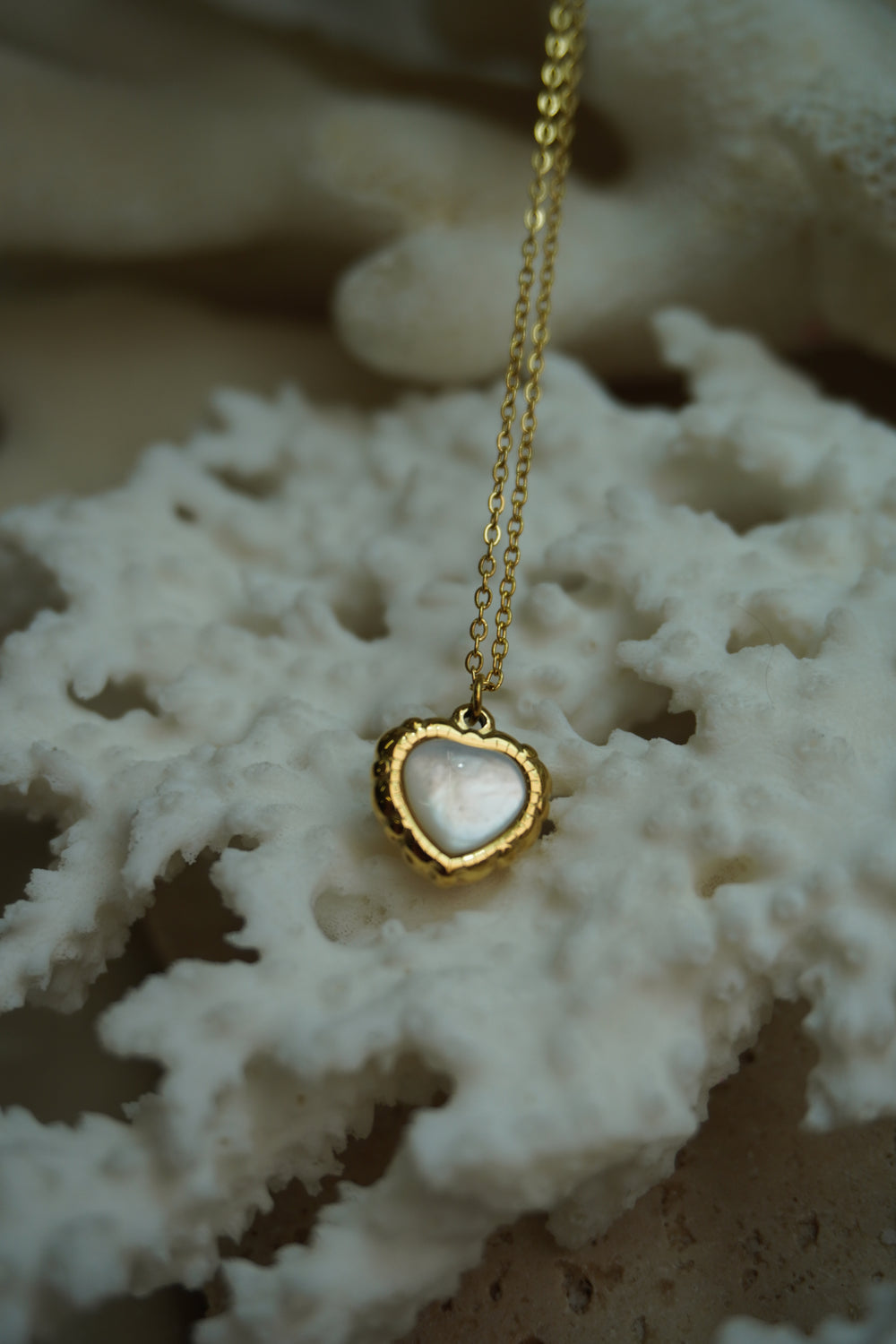 Alternate view: gold-tone fine chain necklace with a pale iridescent heart centre and a textured, scalloped-looking border.