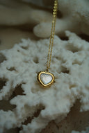 Alternate view: gold-tone fine chain necklace with a pale iridescent heart centre and a textured, scalloped-looking border.