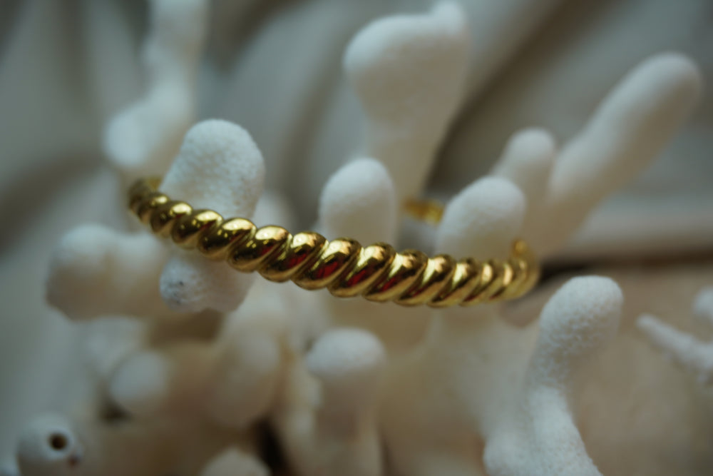 Gold-tone open cuff with rounded diagonal twisted ridges.