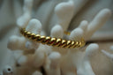 Gold-tone open cuff with rounded diagonal twisted ridges.