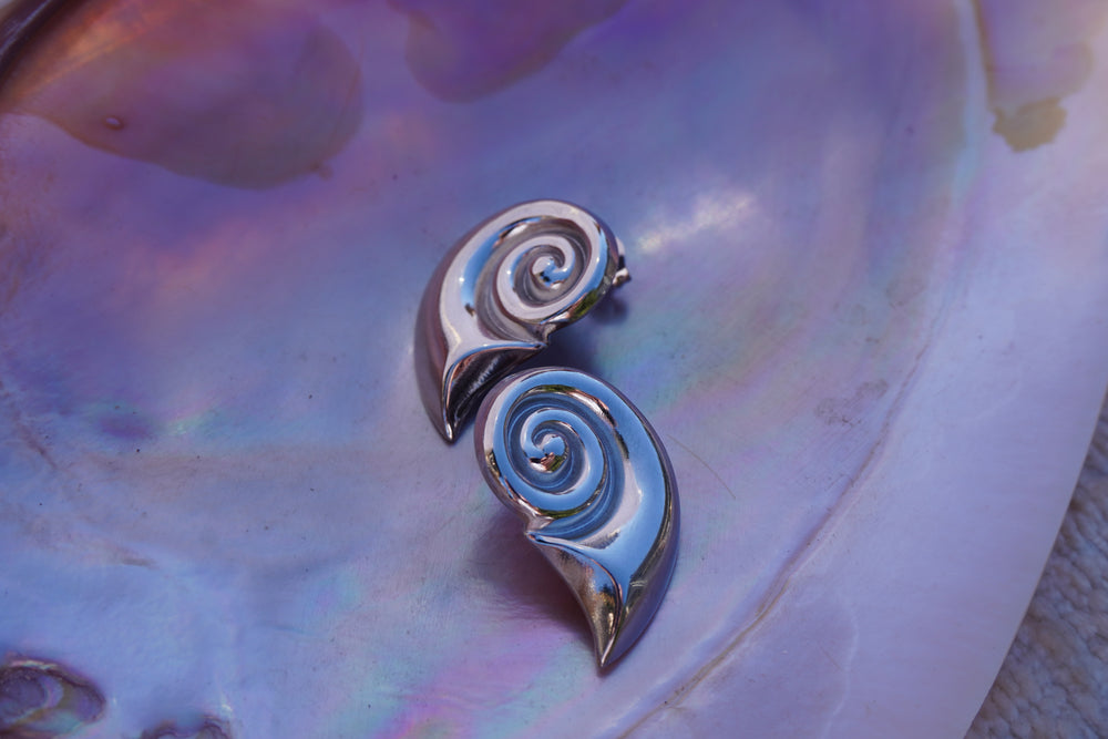 Silver-tone sculptural spiral stud earrings tapering into curved pointed tails.