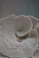 Gold-tone crescent moon necklace with multicoloured round accents and scattered dimpled details.