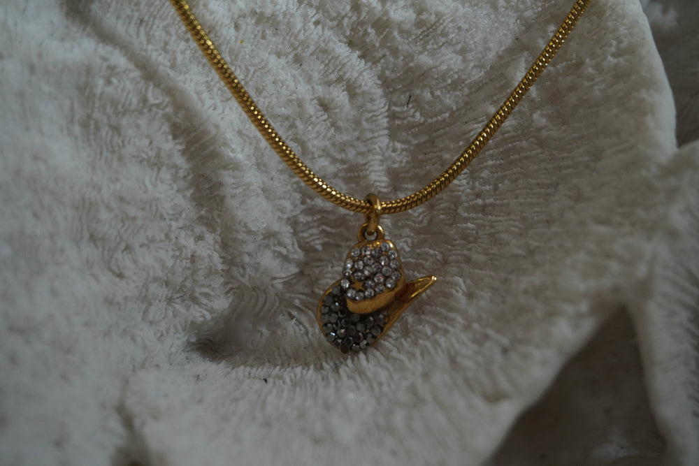 Alternate view: gold-tone necklace with a miniature western hat pendant covered in dark and bright details.
